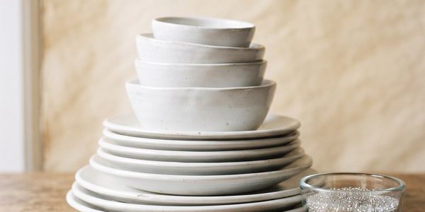 Stos białych talerzy i misek ceramicznych obok miseczki z mikrokulkami szklanymi
